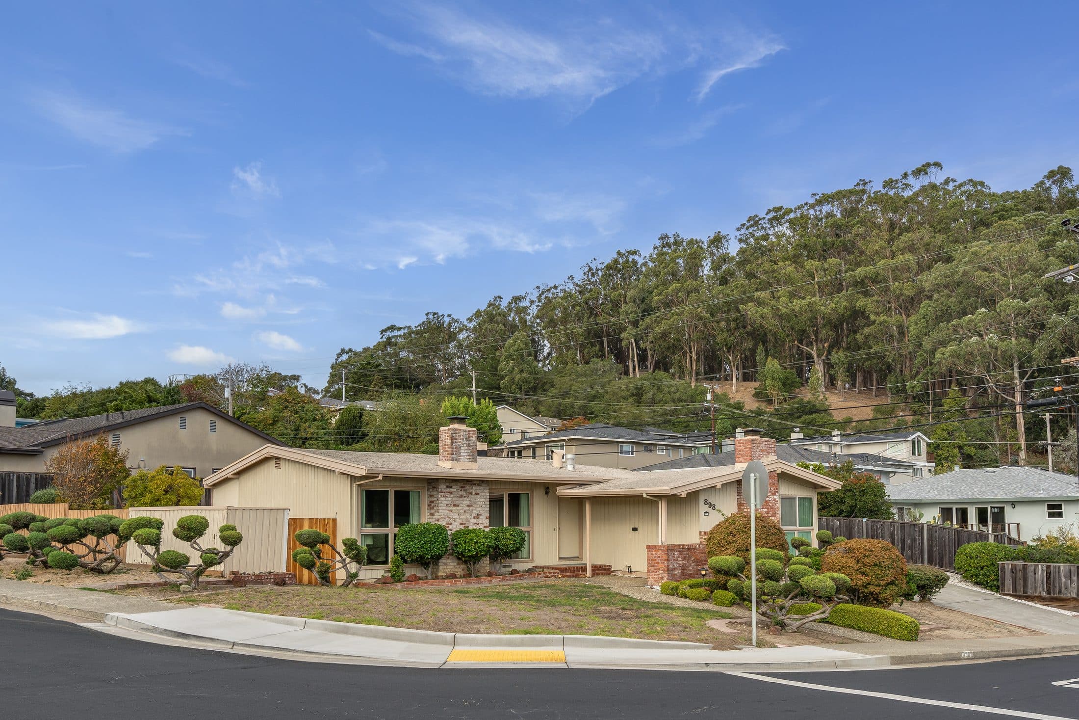 898 Lomita Avenue on its corner lot, with wooded hills behind.